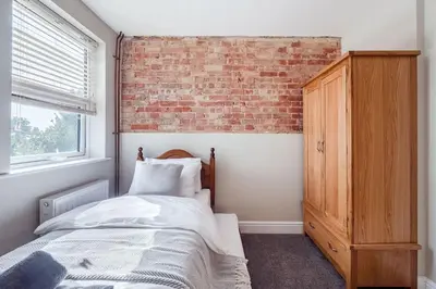 a bedroom with a bed and a brick wall at Host & Stay - Sherrington Road Abode in Ipswich