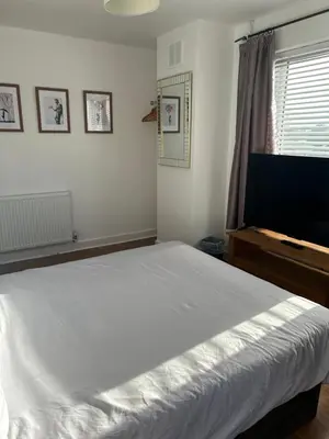 a bedroom with a large white bed and a window at The Poacher in Stevenage
