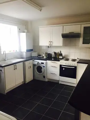 a kitchen with white cabinets and a black tile floor at The Poacher in Stevenage
