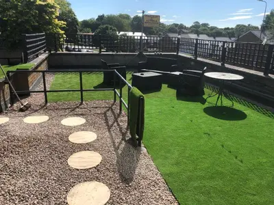a patio with a table and chairs and grass at The Poacher in Stevenage