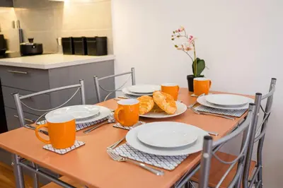 a wooden table with plates of food and orange cups at Host & Stay - Maple Court in Ipswich