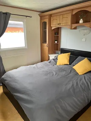 a large bed in a room with a window at Cosy Caravan near the beach in Walton-on-the-Naze