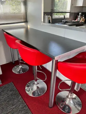 a kitchen with two red bar stools under a counter at Cosy Caravan near the beach in Walton-on-the-Naze