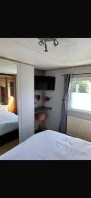 a bedroom with a bed and a window at Cosy Caravan near the beach in Walton-on-the-Naze