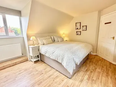 a bedroom with a large bed and a window at Greenacre Lodge - cosy, dog-friendly rural home with private garden in Redgrave