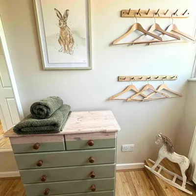 a bedroom with a dresser and hangers at Greenacre Lodge - cosy, dog-friendly rural home with private garden in Redgrave