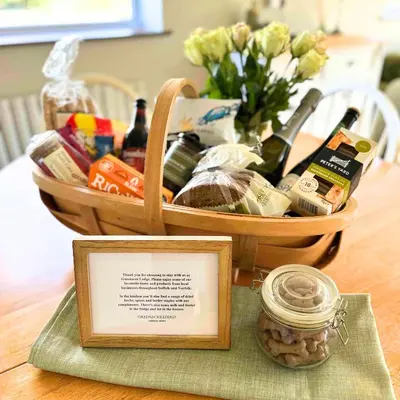 a basket filled with wine bottles and a jar on a table at Greenacre Lodge - cosy, dog-friendly rural home with private garden in Redgrave