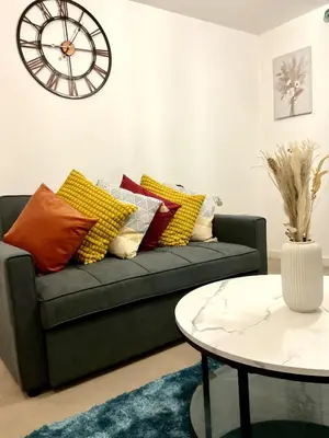 a living room with a couch and a clock on the wall at Ocean-homestay in Colchester