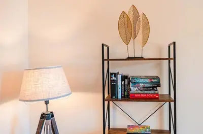 a lamp and a book shelf with books at Spacious & Elegant 3BR Home Near Ipswich City Centre in Ipswich