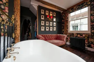 a bedroom with a bed and a couch and a window at Charming Tudor riverside house in Wivenhoe