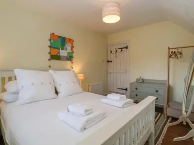 a bedroom with a white bed with towels on it at 6 The Whinlands in Leiston
