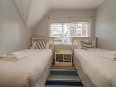 two beds in a small room with a window at 6 The Whinlands in Leiston