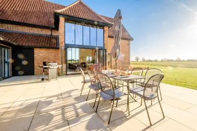 a patio with a table and chairs on a roof at Upper Barn - a large family house by Aldeburgh Coastal Cottages in Ufford