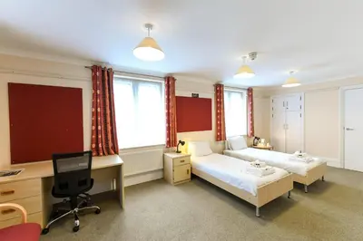 a bedroom with two beds and a desk and a computer at Selwyn College, Cambridge in Cambridge