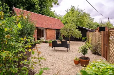 a patio with a black chair in a garden at Guest House in Audley End in Saffron Walden