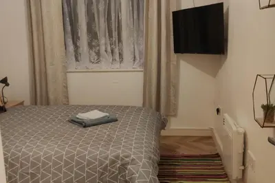 a bedroom with a bed with a television and a window at Apartment - Sleeps 4 - Parking - WiFi in Colchester
