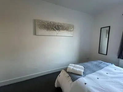 a white bedroom with a bed and a picture on the wall at Hill Grove 2 Bedroom Apartment in Leigh-on-Sea