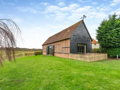 an old black barn with a cross on the roof at Oak Cottage in Ware