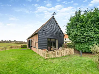 a black barn with a cross on the roof at Oak Cottage in Ware