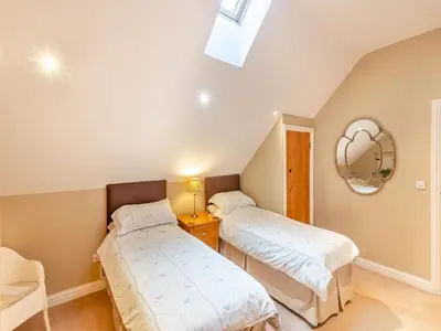 two beds in a room with a mirror at Oak Cottage in Ware