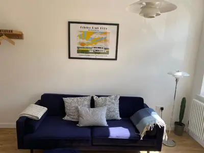 a blue couch in a living room with a picture on the wall at The Studio in Frinton-on-Sea