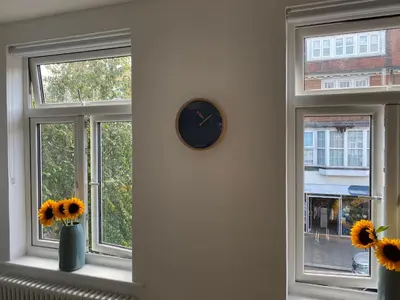 a clock on a wall next to two windows with sunflowers at The Studio in Frinton-on-Sea