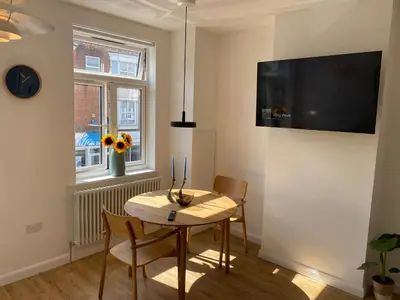 a dining room with a table and chairs and a clock at The Studio in Frinton-on-Sea