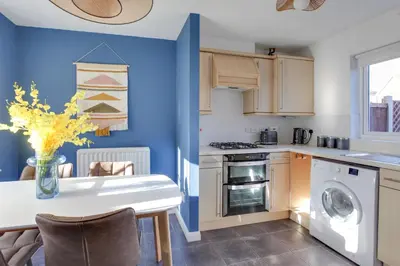 a kitchen with blue walls and a table with a vase of flowers at Cosy Two bedroom house - Chelmsford - Free Parking and Wifi in Chelmsford