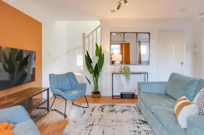 a living room with a blue couch and two chairs at Cosy Two bedroom house - Chelmsford - Free Parking and Wifi in Chelmsford