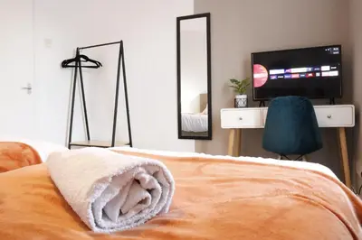 a bedroom with a bed and a tv and mirror at Spacious 2BR Apartment Central Colchester Near Station Fast WIFI in Colchester