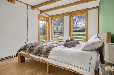 a bedroom with a large bed in a room with windows at Cabin in the countryside in Sible Hedingham