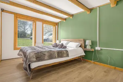 a bedroom with a bed in a room with green walls at Cabin in the countryside in Sible Hedingham