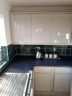 a kitchen with white cabinets and a tea kettle at Lotus House in Needingworth