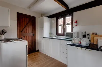 a kitchen with white cabinets and a wooden door at Birds Farm in Colchester