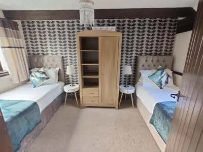 a bedroom with two beds and a book shelf at Birds Farm in Colchester