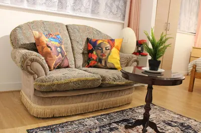 a couch with pillows and a table in a living room at House - Sleeps 10 - Garden - Parking in Romford