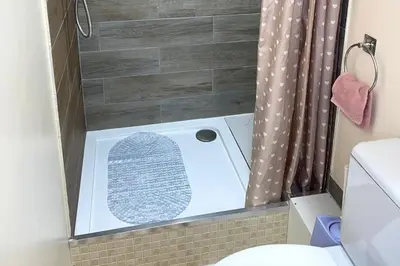 a bathroom with a shower with a toilet in it at House - Sleeps 10 - Garden - Parking in Romford