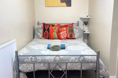 a small bedroom with a bed with colorful pillows at House - Sleeps 10 - Garden - Parking in Romford