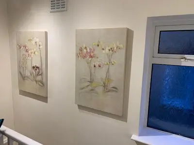 three paintings of flowers on a wall next to a window at Contractor & Family Friendly House Romford in Havering atte Bower