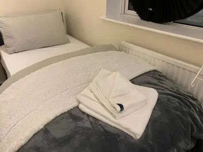 a bed with a white towel on top of it at Contractor & Family Friendly House Romford in Havering atte Bower