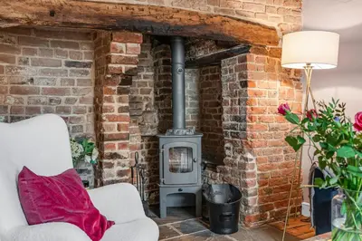 a brick fireplace in a living room with a chair and a stove at The Blue Anchor House - close to London in Hertford