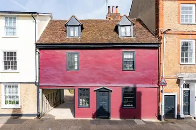 a red building with a black door and windows at The Blue Anchor House - close to London in Hertford