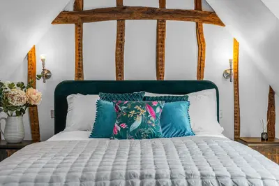 a bed with blue and white pillows on it at The Blue Anchor House - close to London in Hertford