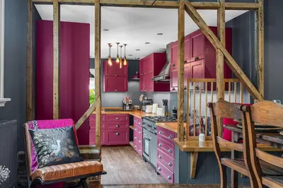 a kitchen with pink cabinets and a wooden table at The Blue Anchor House - close to London in Hertford