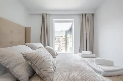 a white bedroom with a bed and a window at Luxury 2 Bedroom Apartment with AC and Parking in Cambridge