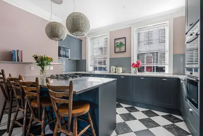 a kitchen with blue cabinets and a checkered floor at London- Large Period Town House with river front in Hertford