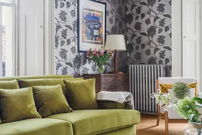 a green couch in a living room with wallpaper at London- Large Period Town House with river front in Hertford
