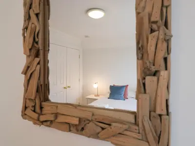 a mirror reflecting a bedroom with a bed with a blue pillow at 9 Church Farm Rise in Aldeburgh