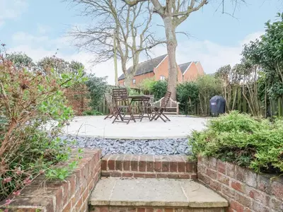 a patio with a table and chairs in a garden at 9 Church Farm Rise in Aldeburgh