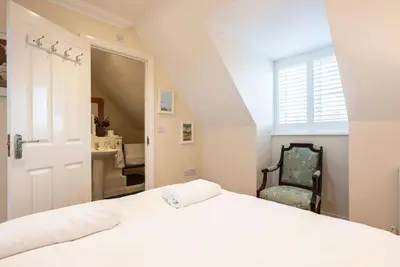 a bedroom with a white bed and a chair at Fromus Rise, Saxmundham in Saxmundham